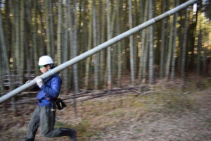 伐った竹を担いで走る学生